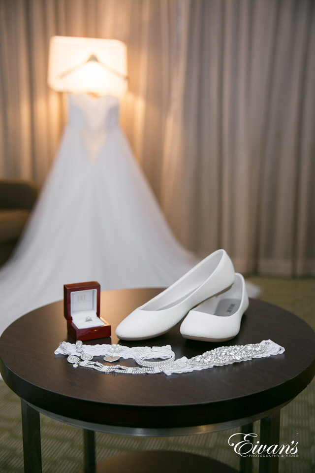 The photographer focuses the camera lens on the bride's shoes, garter, bracelet and weddings ring in a depth of field shot.